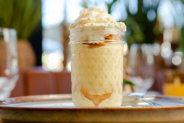 Banana pudding served in a glass jar with whipped cream and wafers
